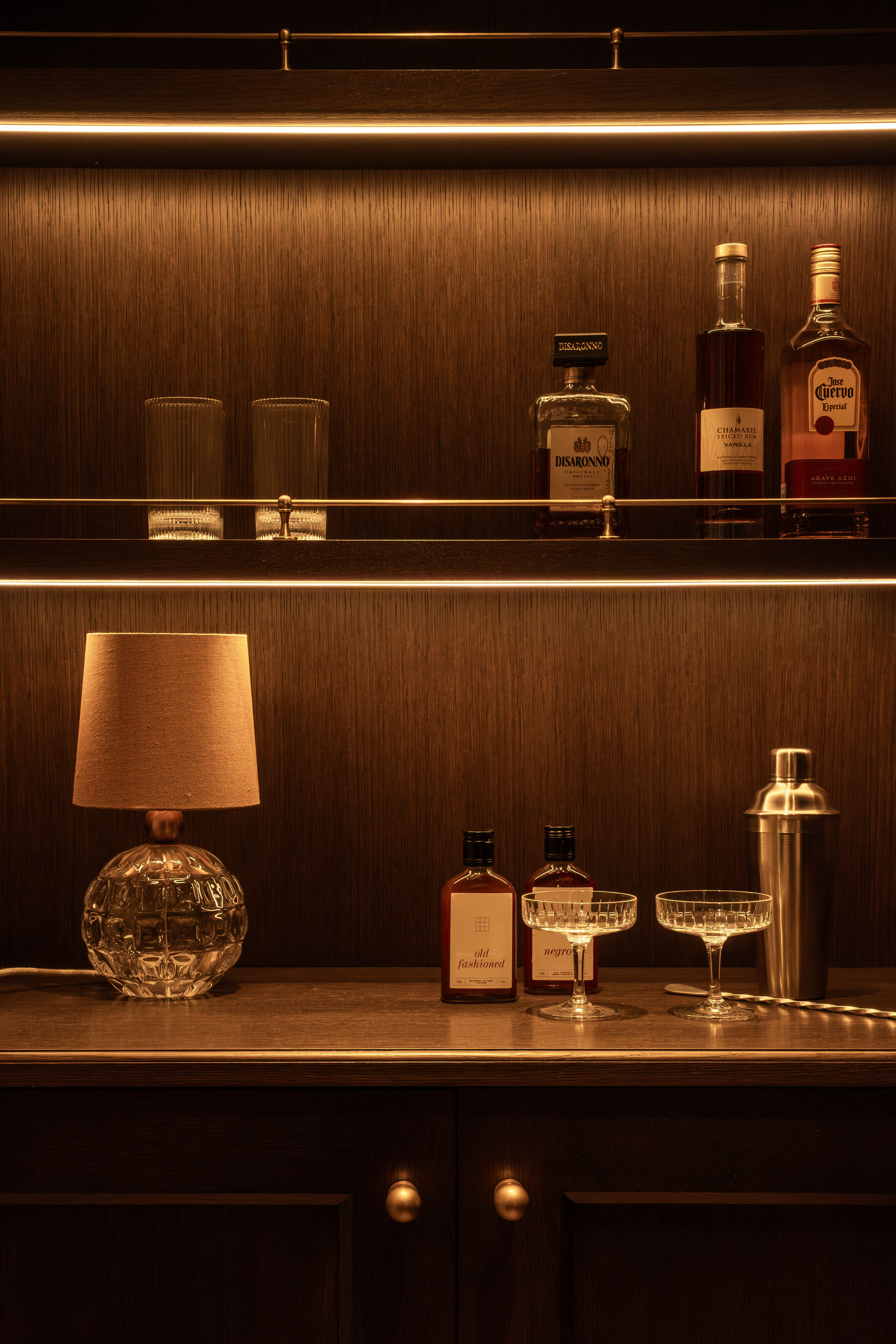 Private bar with backlit oak shelving and brass gallery rail