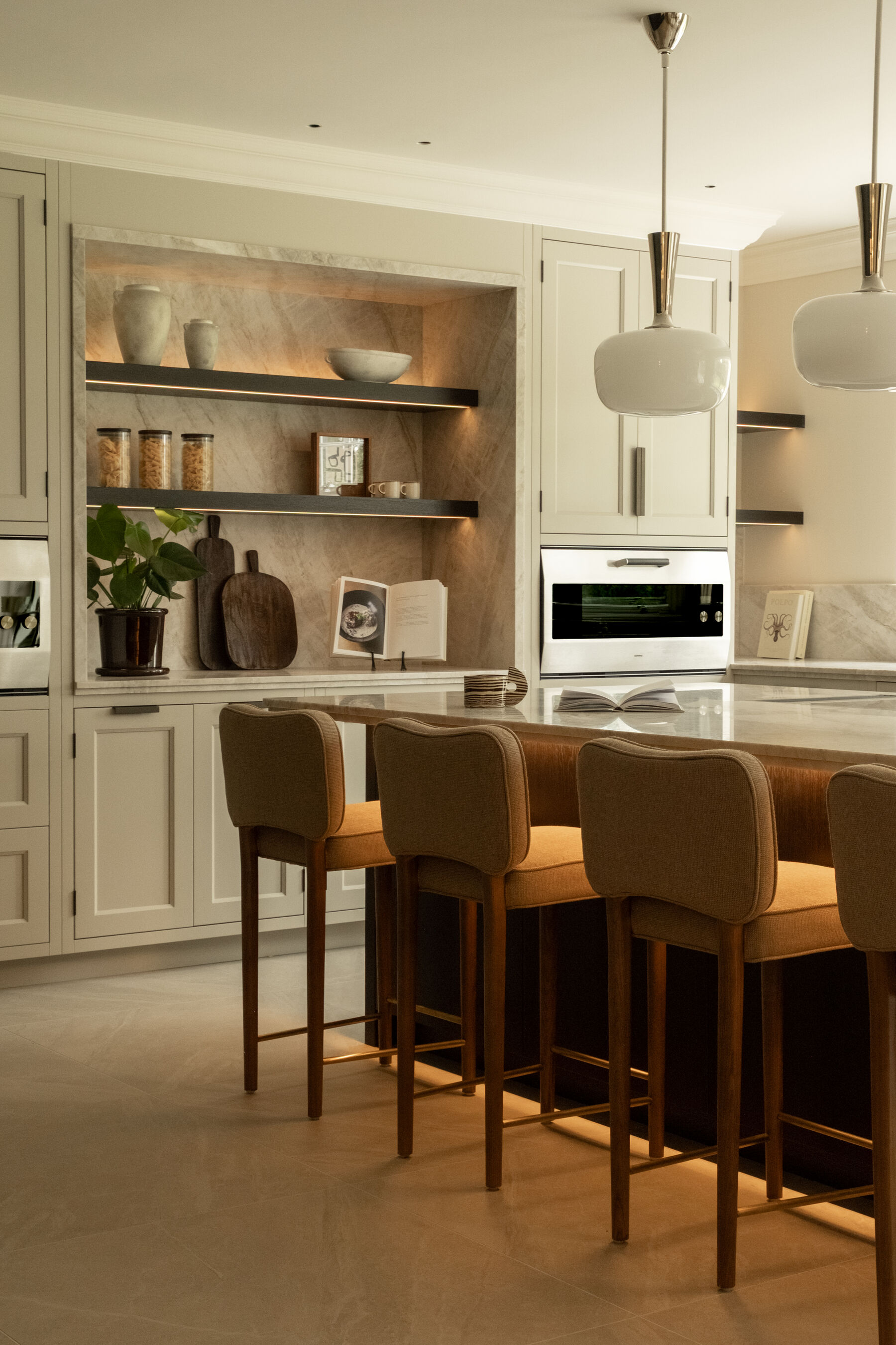 Kitchen breakfast bar with upholstered stools and lit stone niche