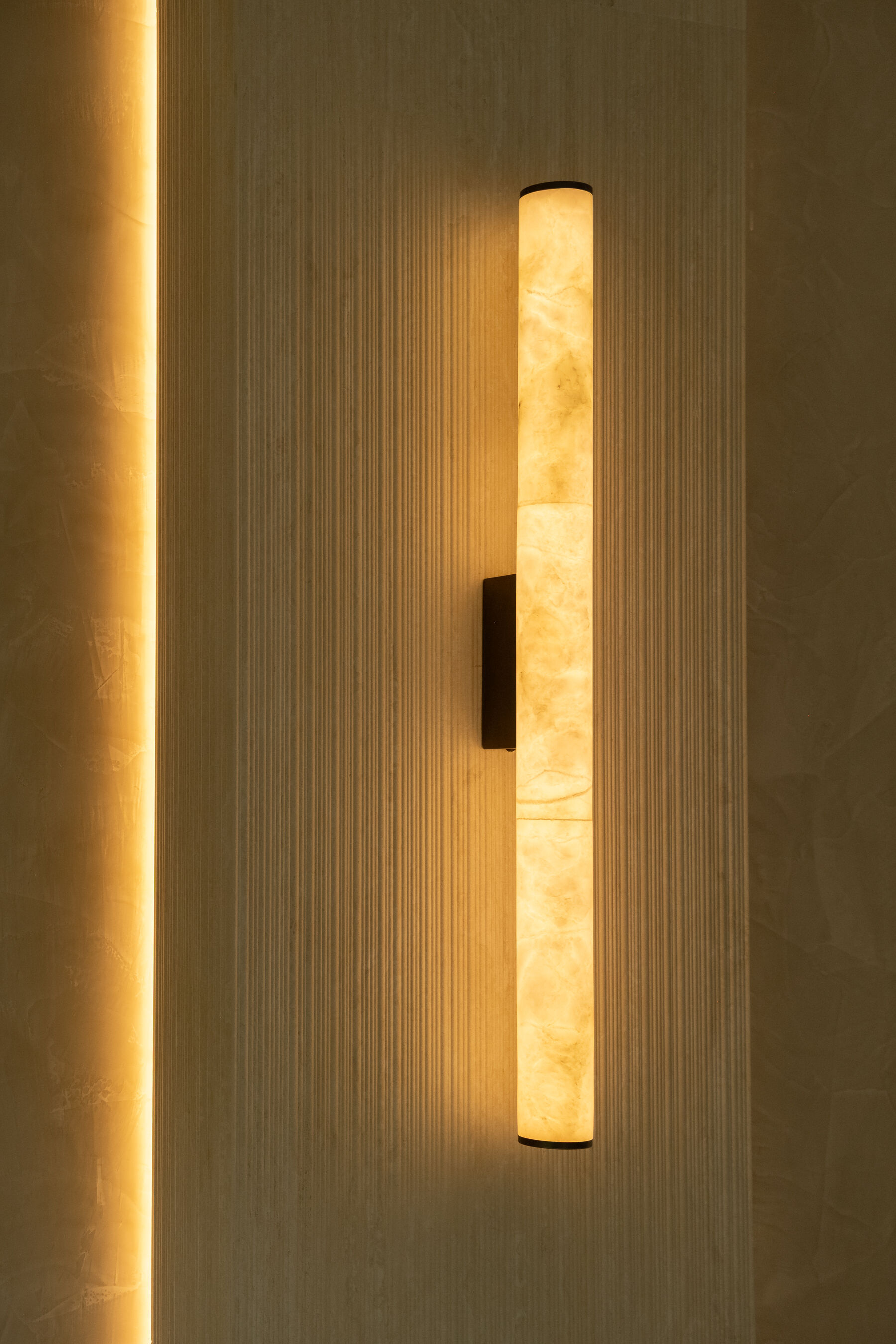 Alabaster wall light against textured tile