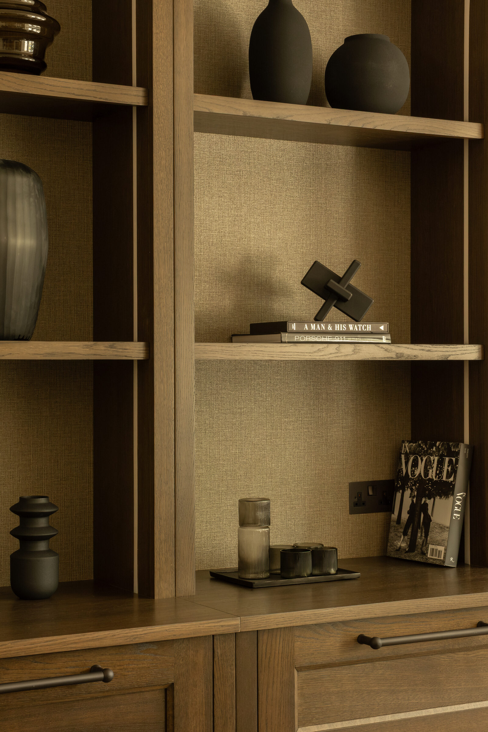 Detail of study shelving with books, objects and textured wall panel