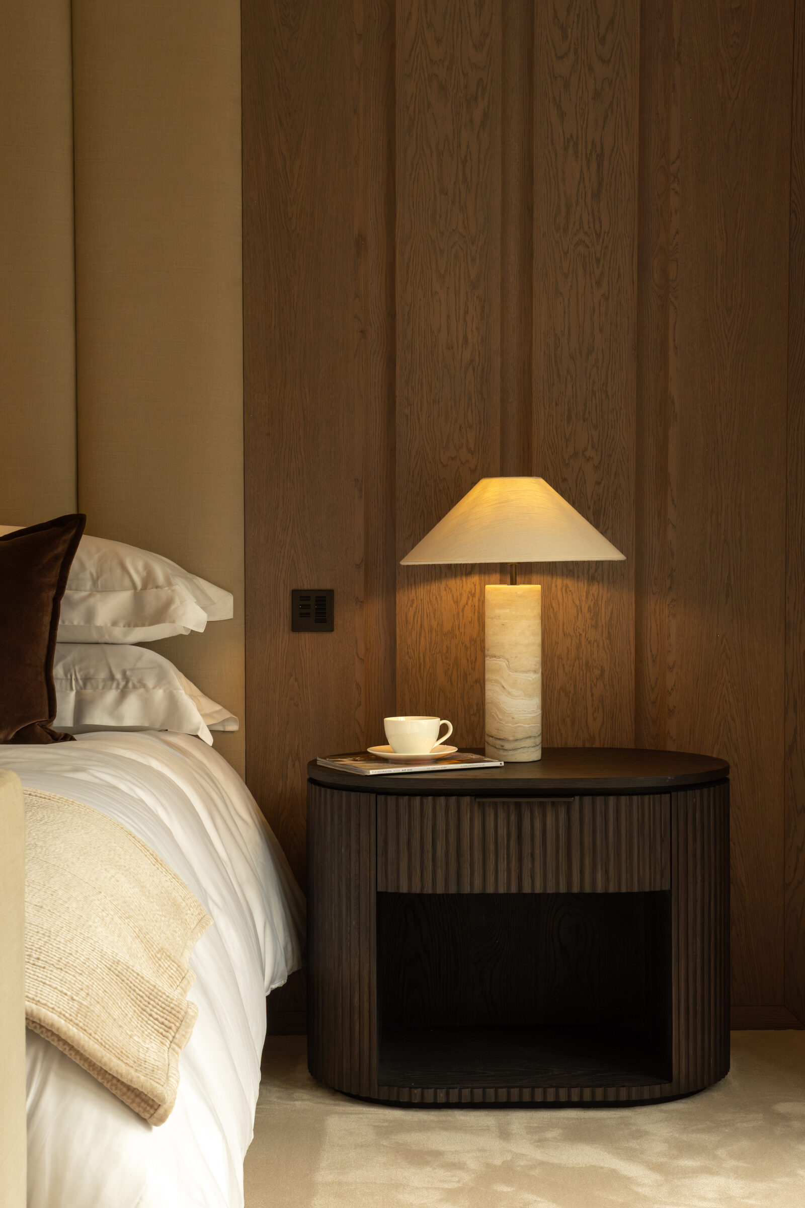 Principal bedroom with panelled oak headboard and marble table lamp